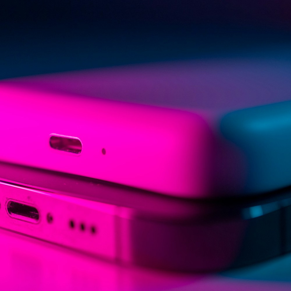 Close-up of stacked smartphones in magenta and blue light for the AURVINCIS contact page.